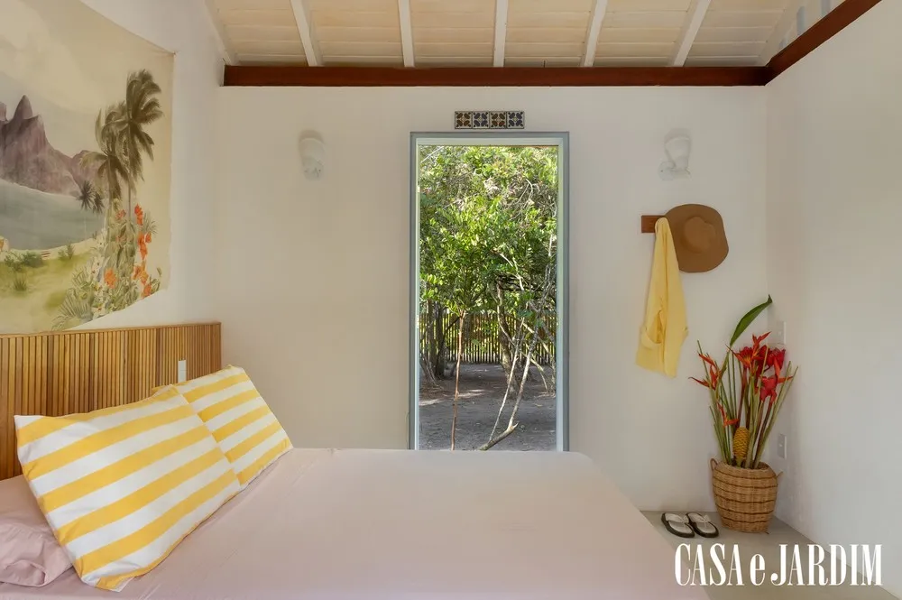 Suíte com almofada listrada e vista para o jardim