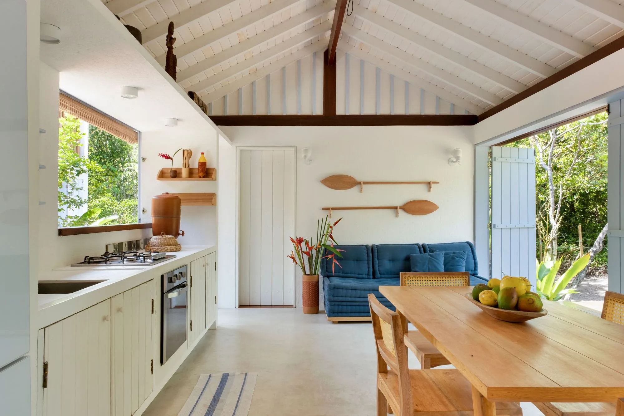 Cozinha e sala integradas, com sofá azul e mesa de jantar