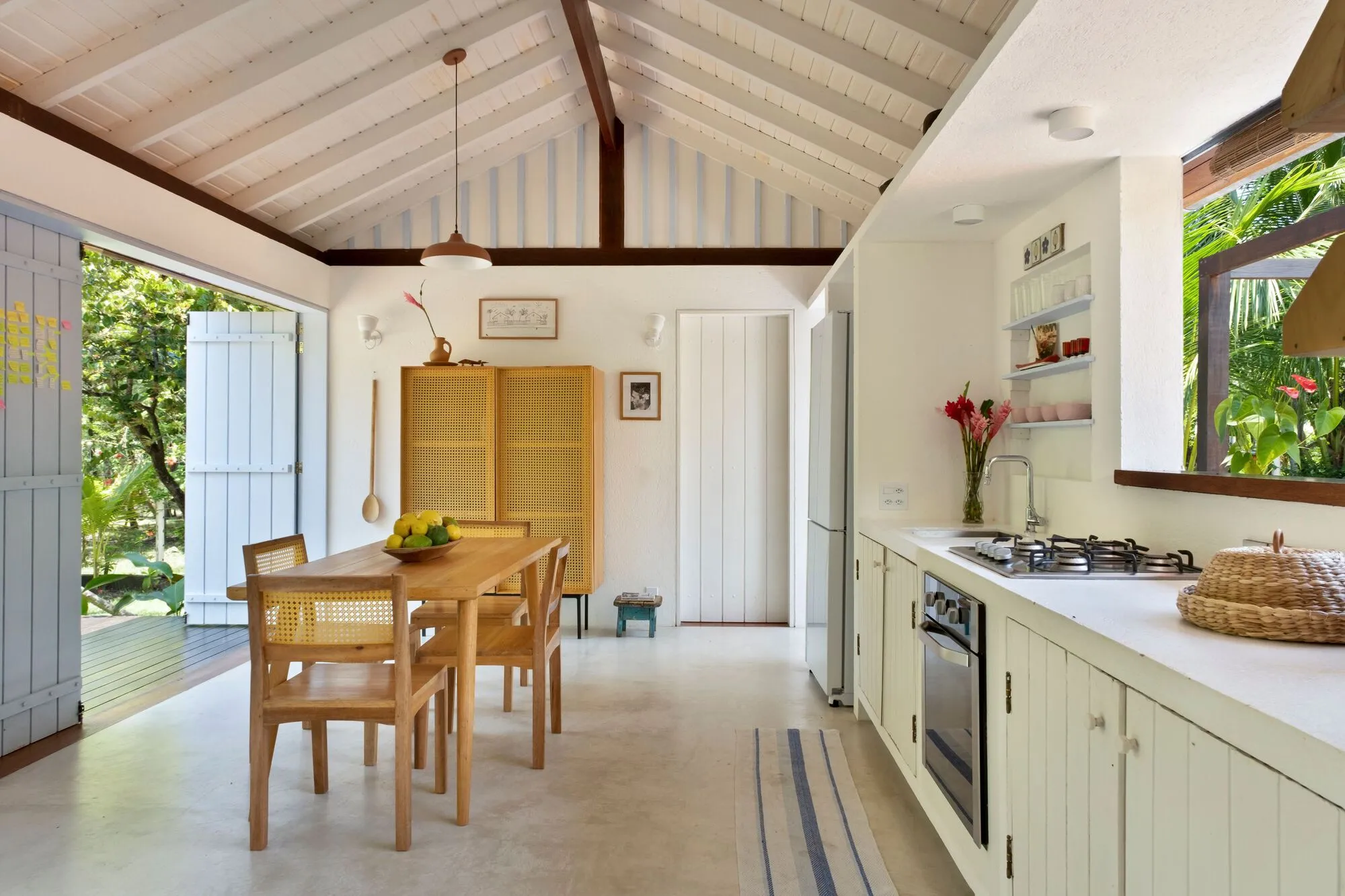 Sala e cozinha em vista longitudinal, com o armário amarelo ao fundo