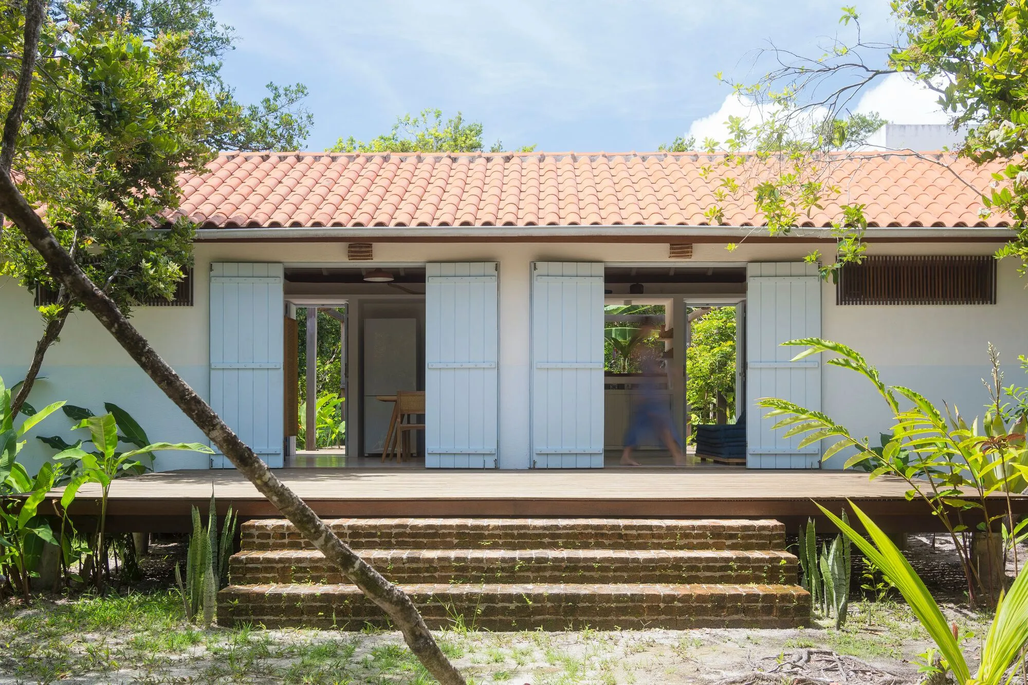 Fachada frontal com as portas abertas e uma pessoa no vão